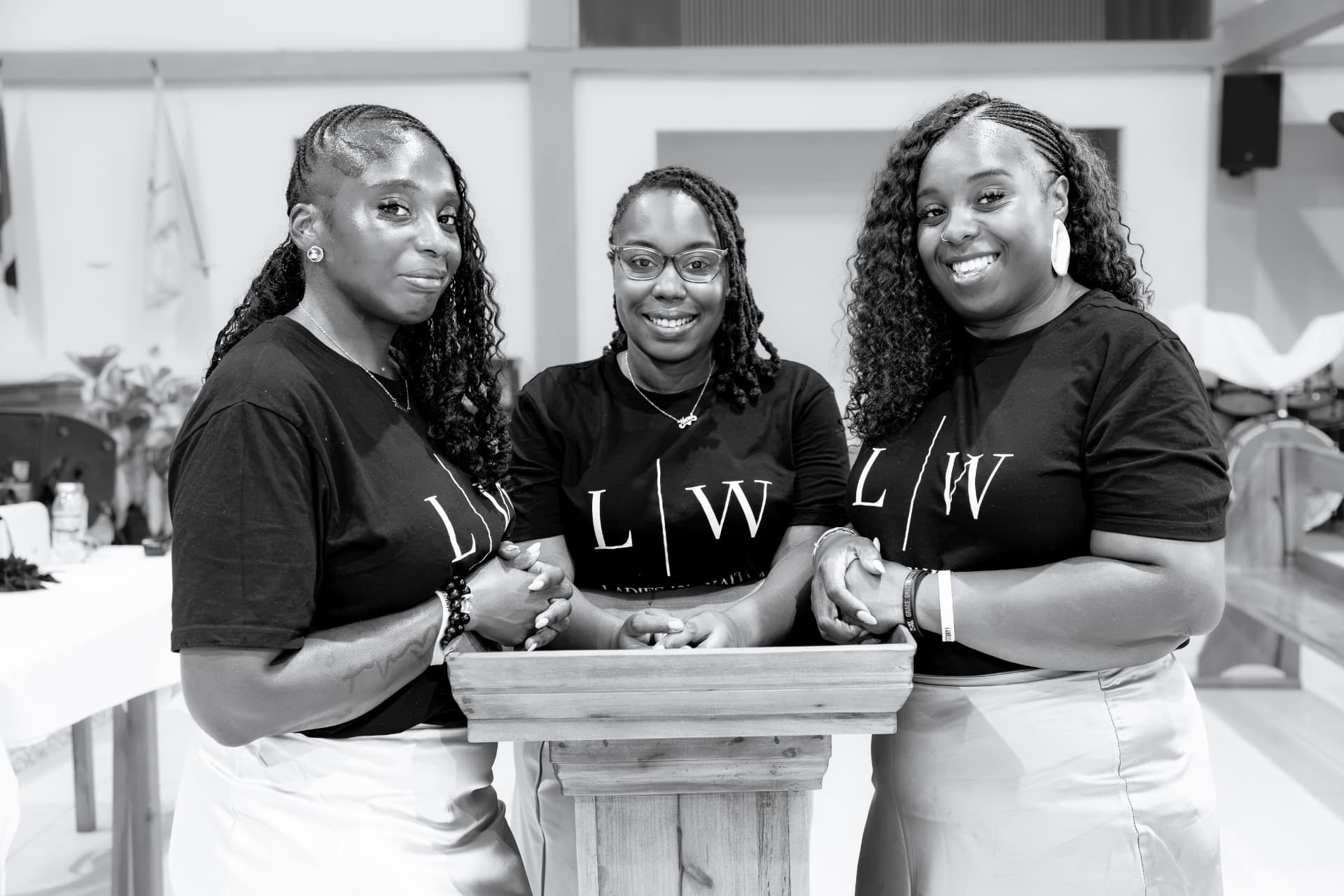 Black and white portrait of three LIW Jamaica leads at the lectern