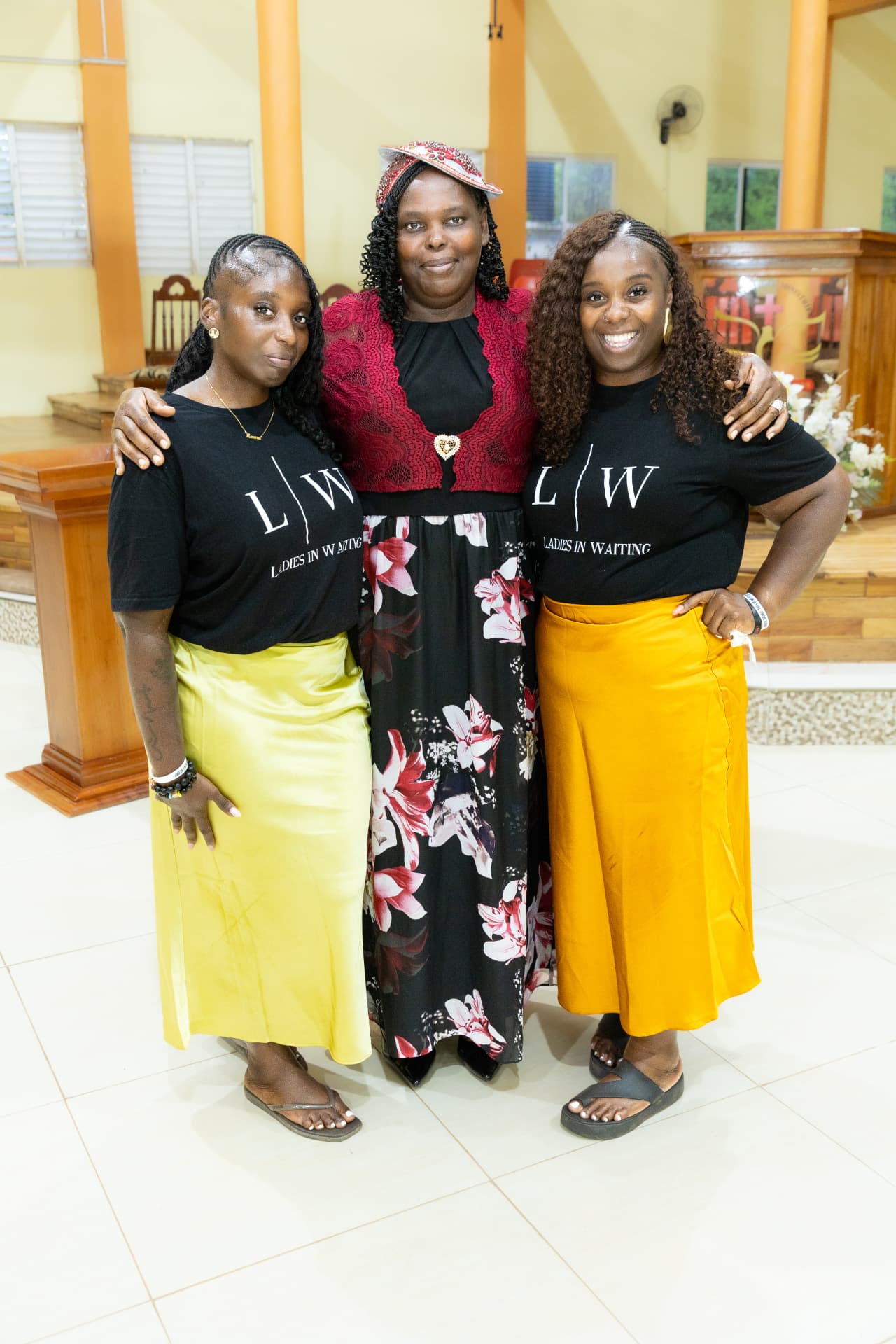 Two LIW Jamaica team members in branded T-shirts standing either side of a guest speaker