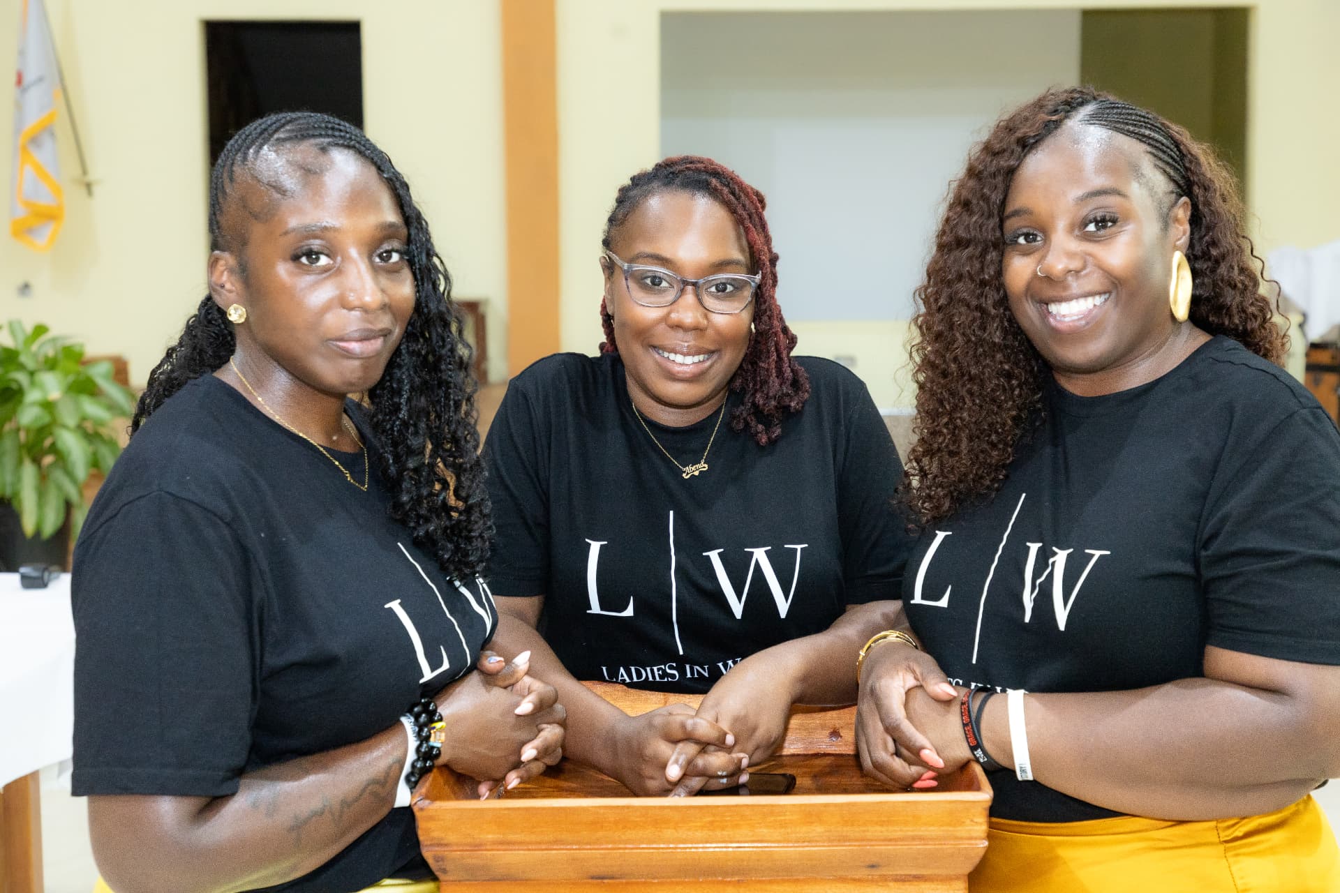 Three LIW Jamaica leads smiling together behind a wooden lectern