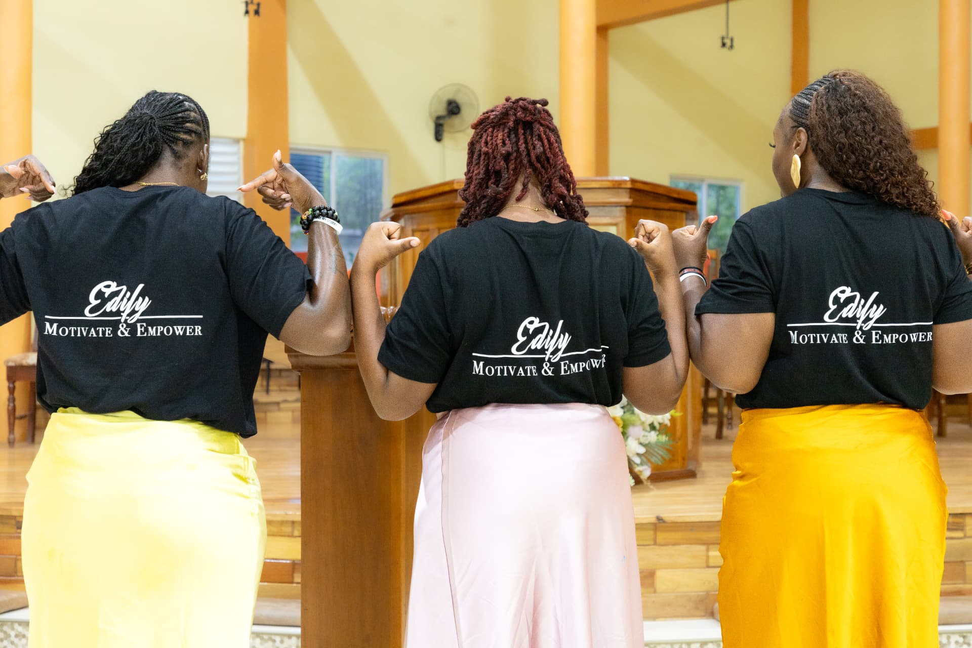 Three team members showing the Edify, Motivate and Empower slogan on the back of their LIW shirts