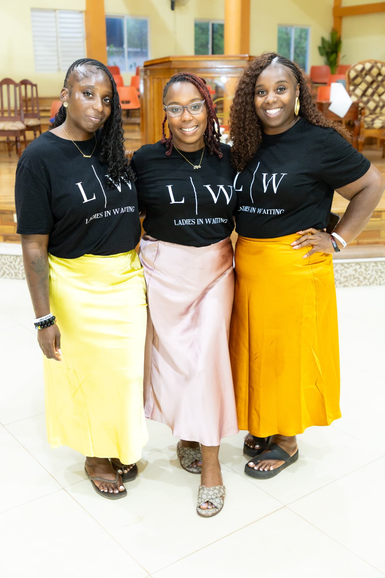 Three LIW Jamaica team members standing together in branded T-shirts at the launch